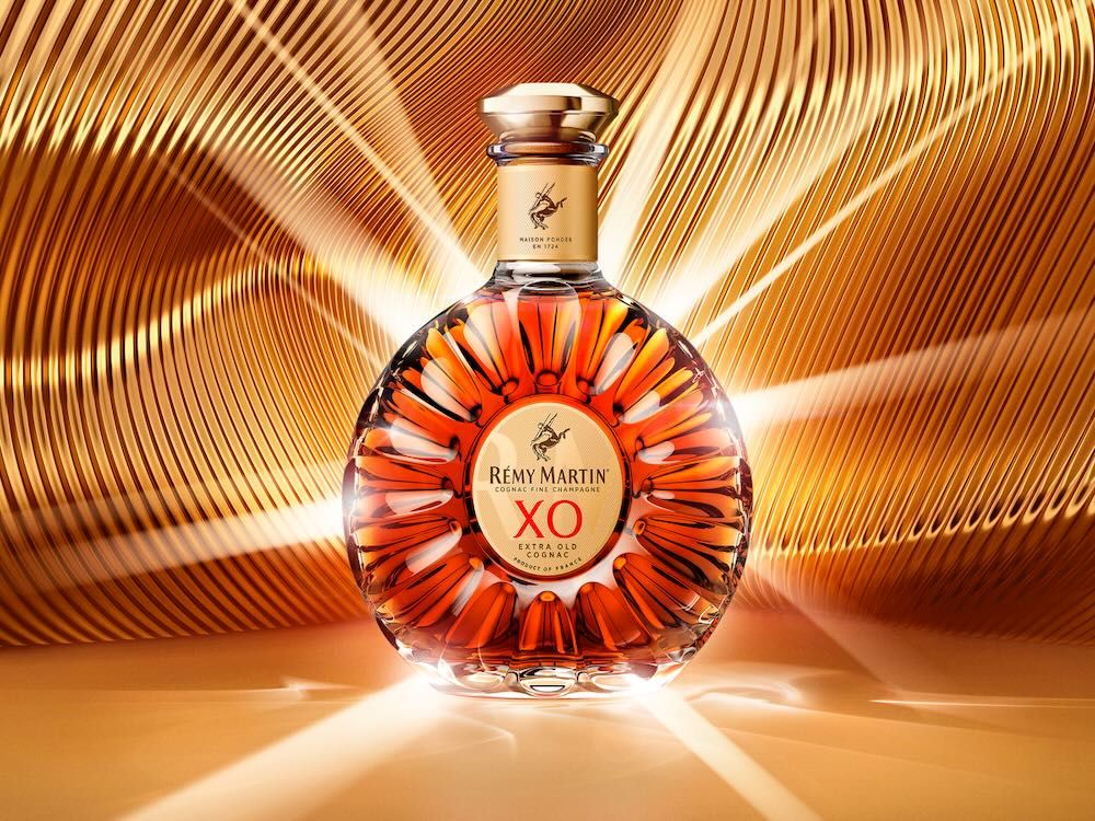 Bouteille Rémy Martin XO sur fond doré chatoyant, célébrant la Journée Internationale du Cognac 2026.