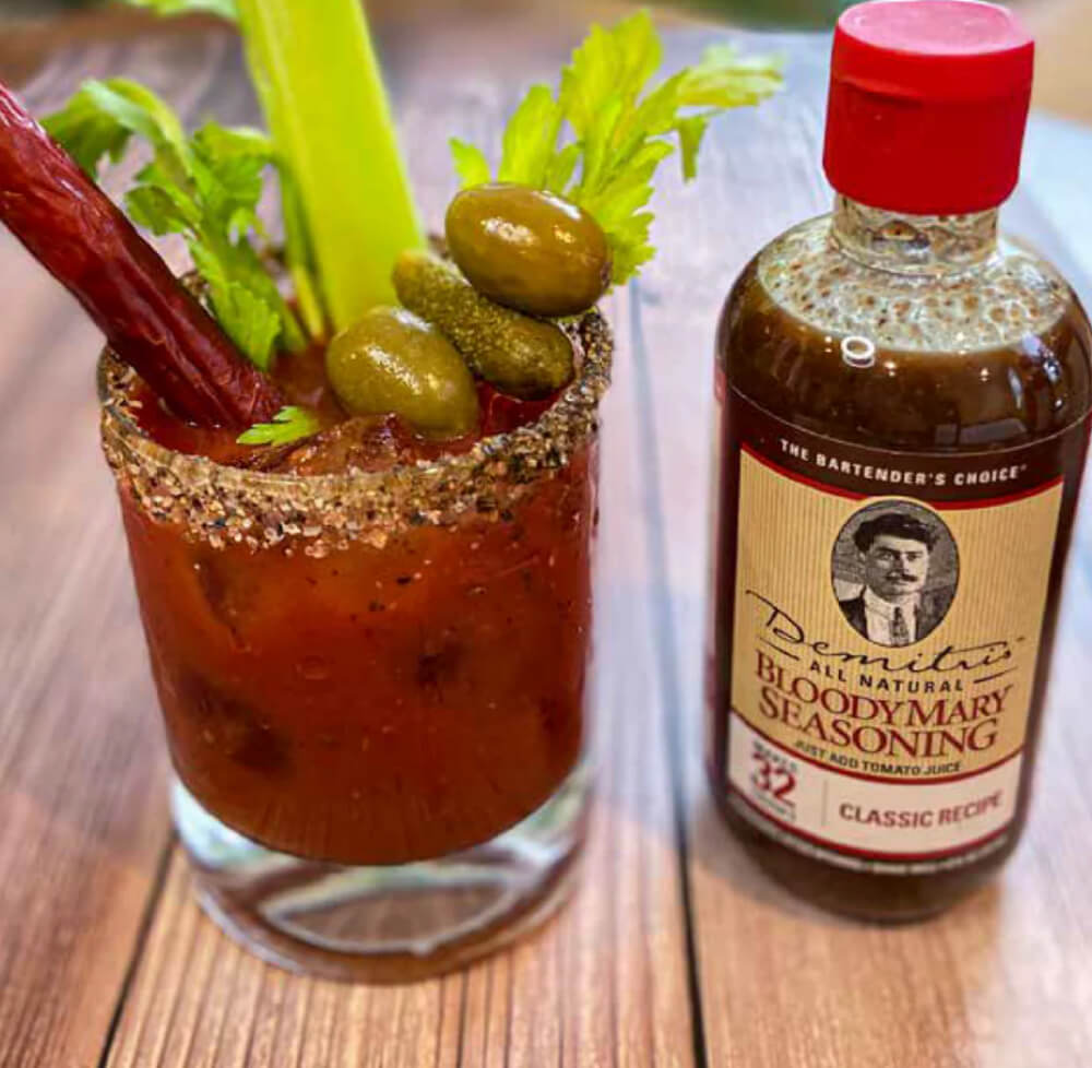 Un Bloody Mary garni de céleri, d'olives et d'un bâtonnet de bœuf, accompagné d'une bouteille d'assaisonnement Bloody Mary de Demitri.