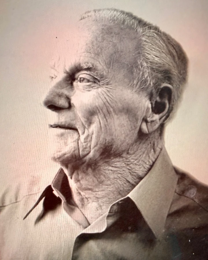 Portrait en noir et blanc d'un homme plus âgé à l'expression pensive, vêtu d'une chemise à col.