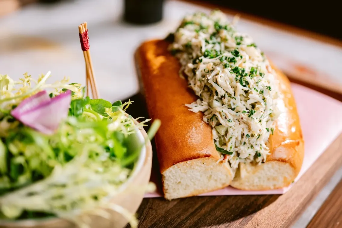 Un délicieux rouleau de crabe garni d'herbes fraîches, servi avec un bol de mesclun.